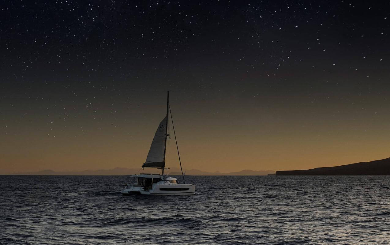 Barca a vela che naviga al tramonto sotto il cielo stellato in acque calme, creando un'esperienza unica in mare.