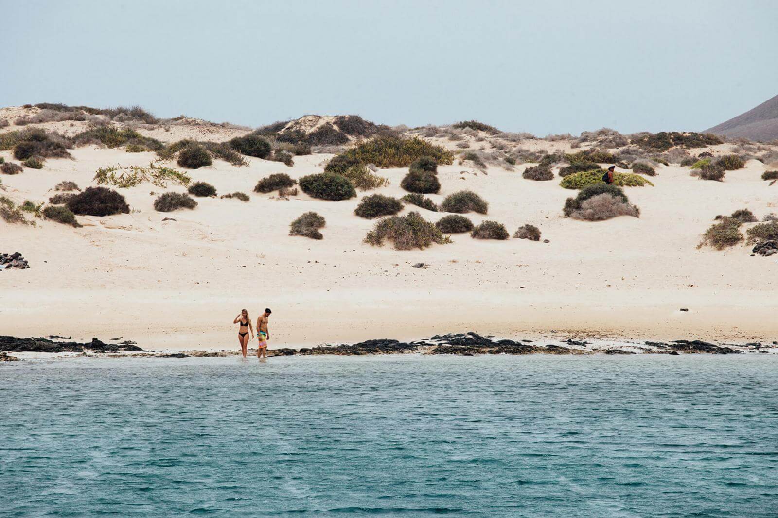 Pareja entrando al mar en una playa de arena blanca