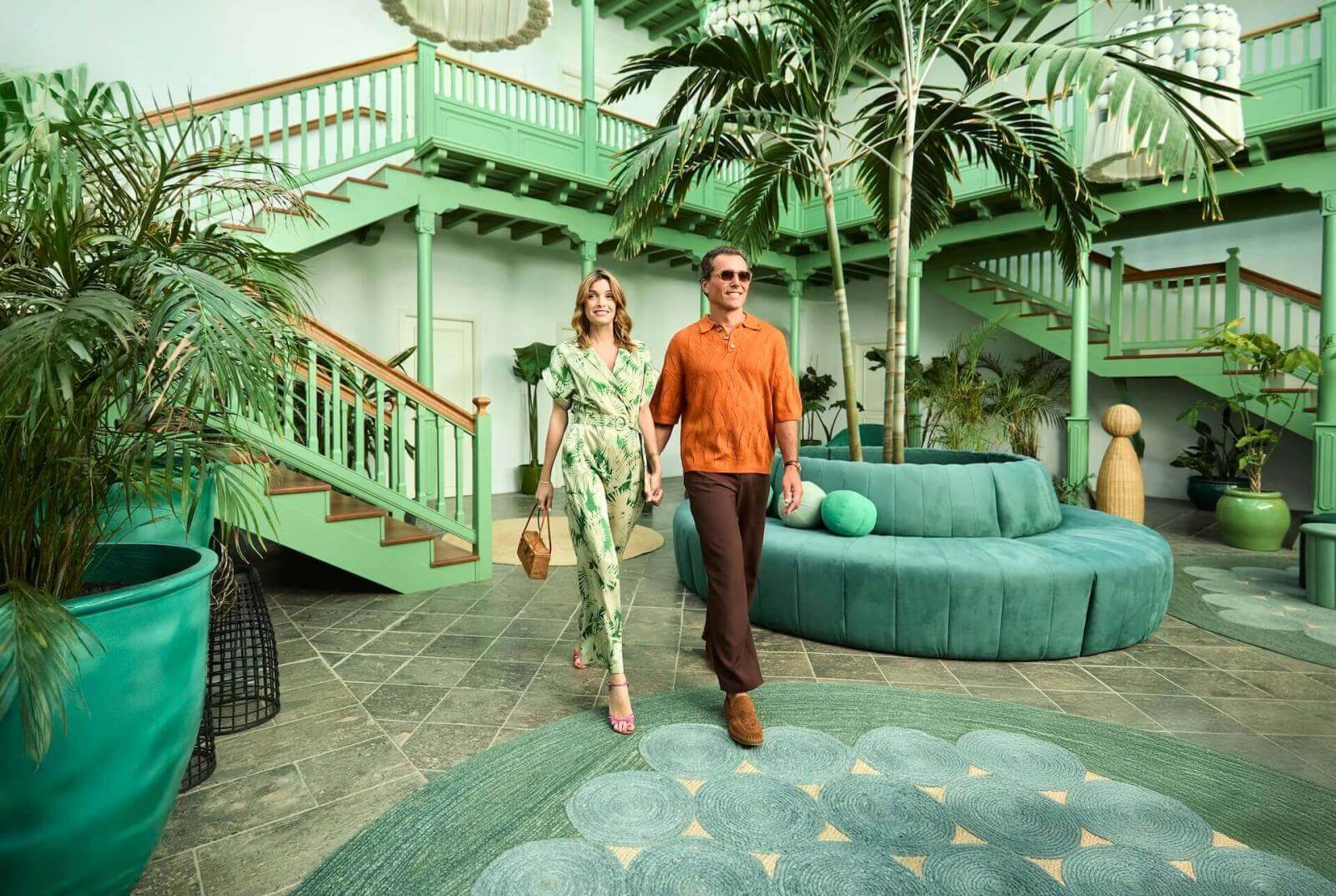 Coppia che cammina in una hall ispirata all'architettura tradizionale delle Canarie, con luce e vegetazione tropicale.