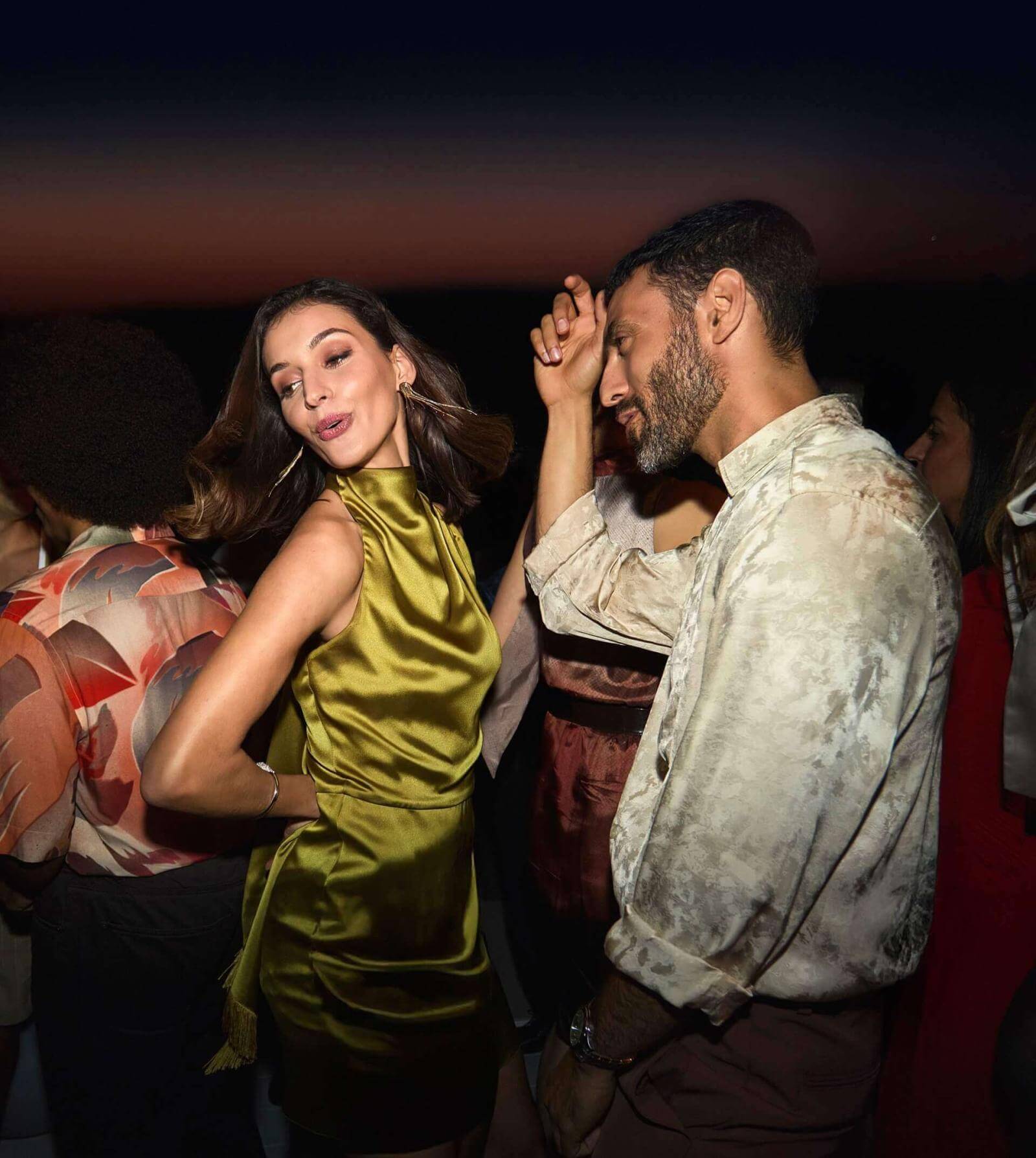 Coppia che balla in terrazza rooftop con vista sul mare al crepuscolo.