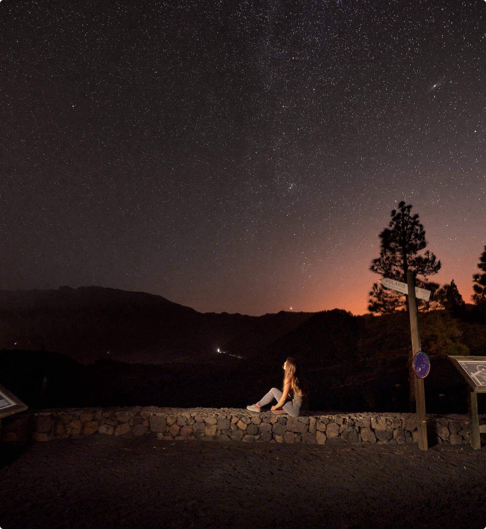 Notte stellata dal belvedere Llano del Jable, La Palma, sagome di montagne e persona che guarda il paesaggio.