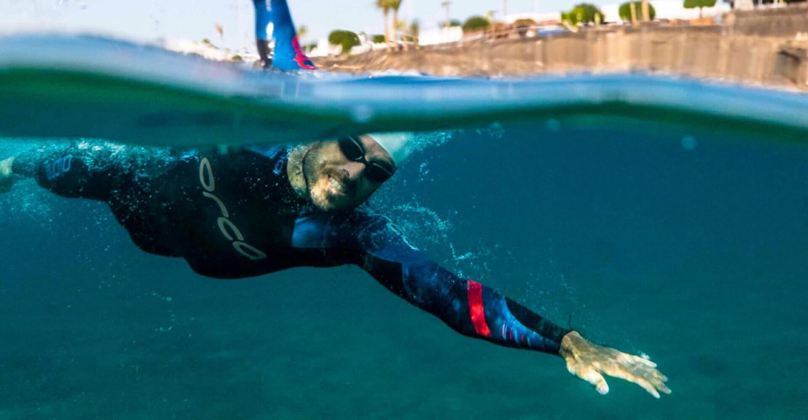 Persona che nuota in acque aperte con una muta in neoprene.