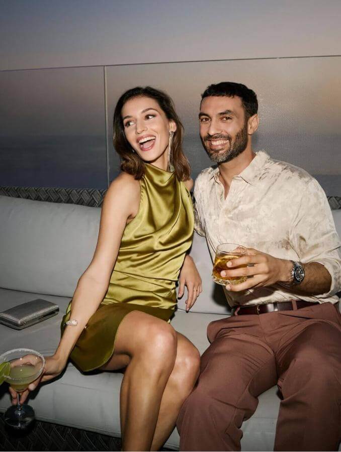 Coppia che si gode un cocktail in terrazza al tramonto con vista sul mare e un'atmosfera elegante.